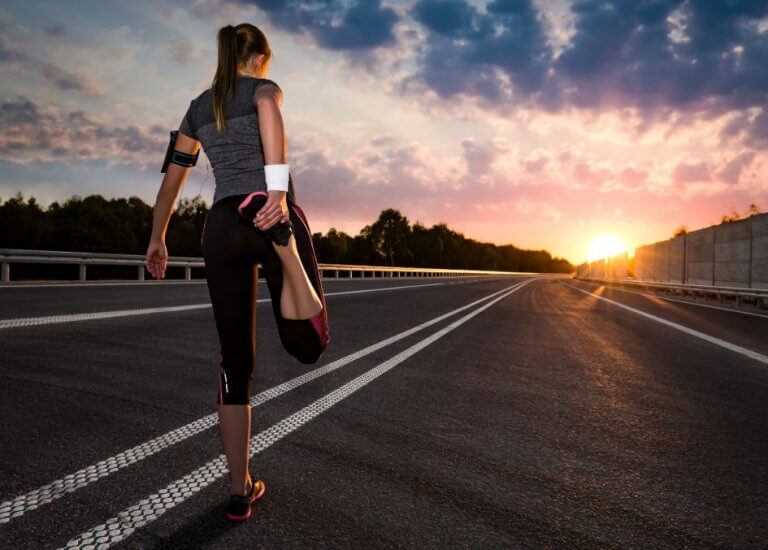 En jente som strekker ut før hun skal løpe.