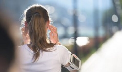 Jente som løper med hodetelefoner.