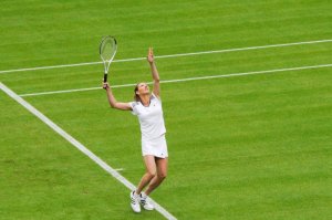 Kvinne spiller tennis på gressmatte.