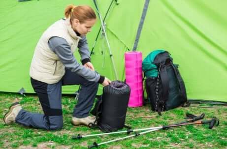 kvinne som pakker sammen soveposen sin i et telt