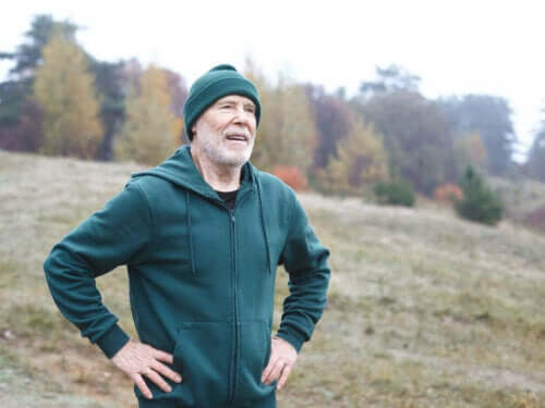 Eldre mann som løper utendørs og har stoppet for å puste ut.