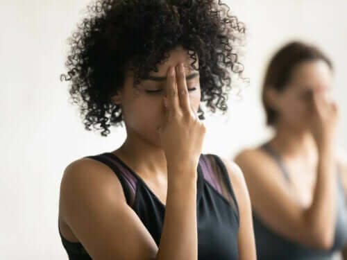 Kvinne med fingrene på pannen, som mediterer for å forbedre pusteteknikken.