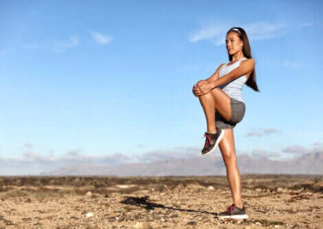 En kvinne står å tøyer ut i naturen.