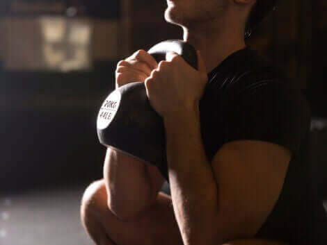 En mann som tar en knebøy med en kettlebell.