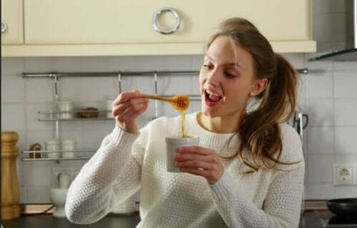 En kvinne som tilsetter honning i teen sin