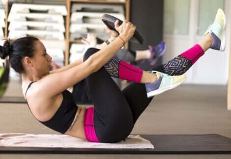 En kvinne som gjør mageøvelser med en vektskive.