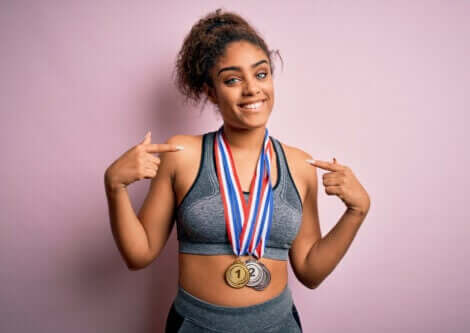 Kvinne iført medaljer som peker på seg selv.